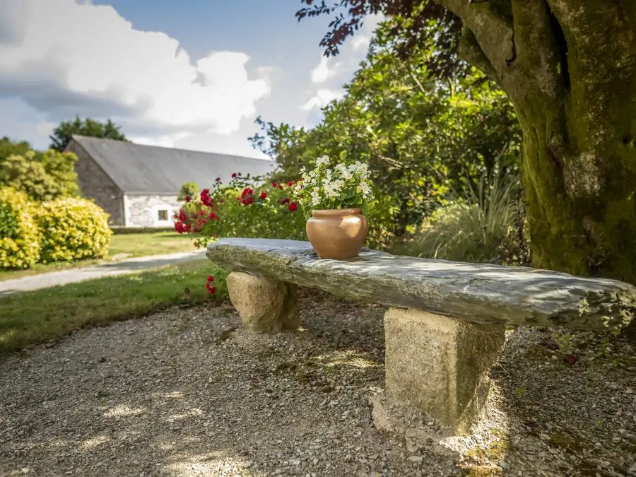 Un banc de pierre avec un pot de fleurs dans le jardin