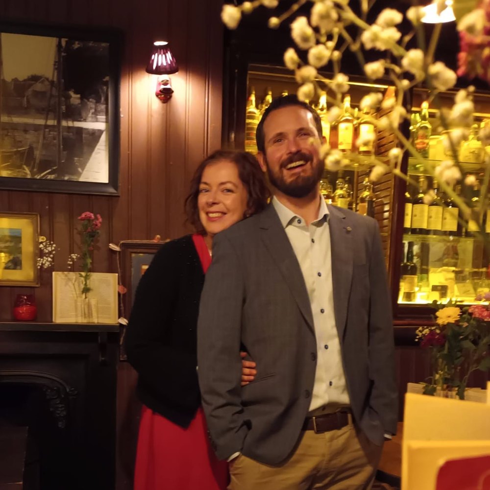 Conor et Corinne riant ensemble dans un pub chaleureux